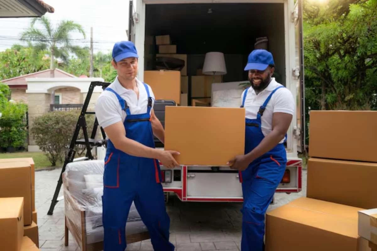 Two professional movers in blue uniforms unloading boxes from a truck in Dubai